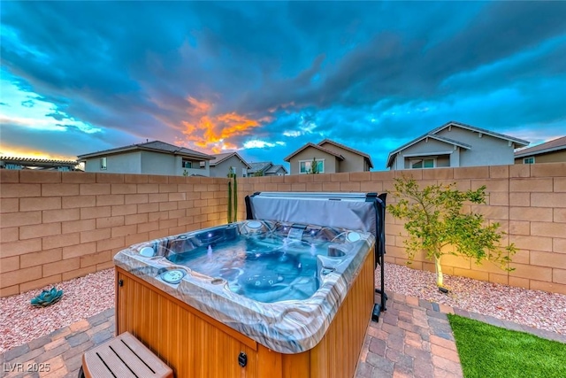 patio terrace at dusk with a fenced backyard and a hot tub