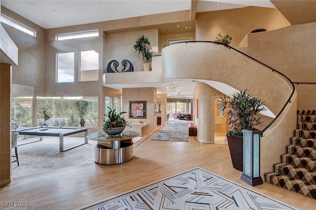 foyer with stairs, wood finished floors, and a towering ceiling