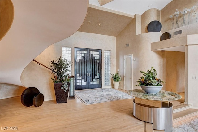 entrance foyer featuring visible vents, a high ceiling, and wood finished floors