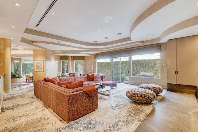 living room with a wealth of natural light, visible vents, recessed lighting, and a raised ceiling