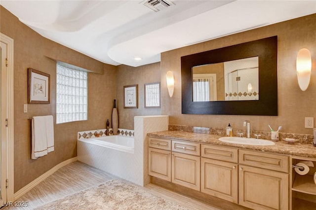 bathroom featuring a bath, visible vents, vanity, and baseboards