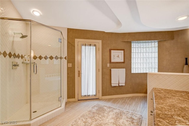 full bathroom with a shower stall, wood finished floors, and baseboards