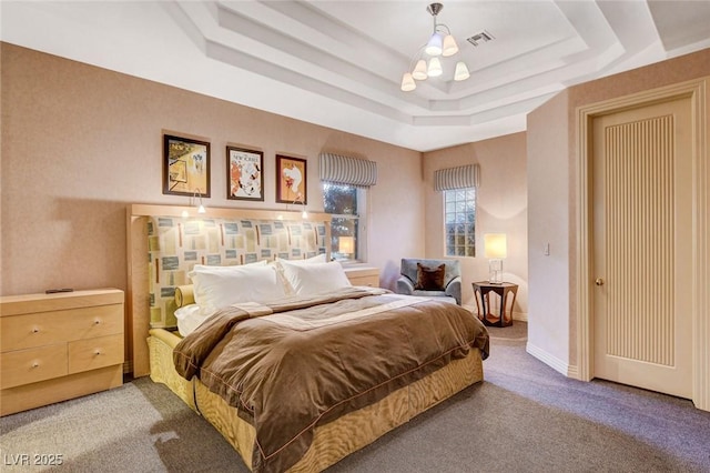 carpeted bedroom featuring visible vents, a raised ceiling, and baseboards