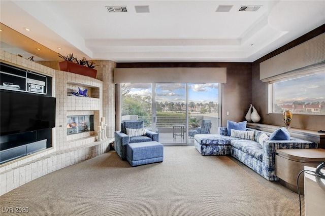 living area featuring visible vents, carpet, and a tray ceiling