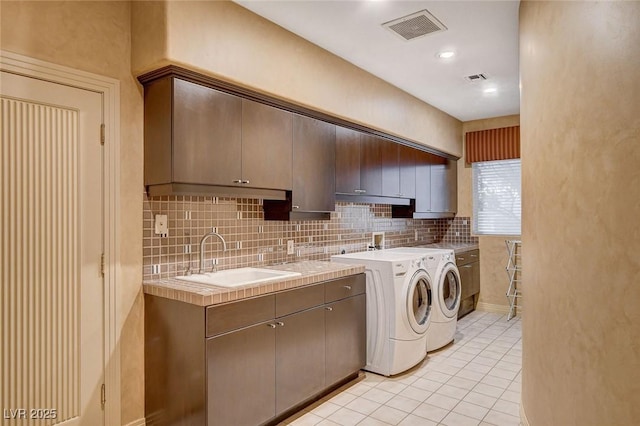 laundry room with light tile patterned floors, visible vents, cabinet space, a sink, and independent washer and dryer