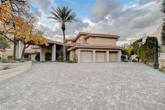 mediterranean / spanish-style house featuring a tiled roof, an attached garage, driveway, and stucco siding