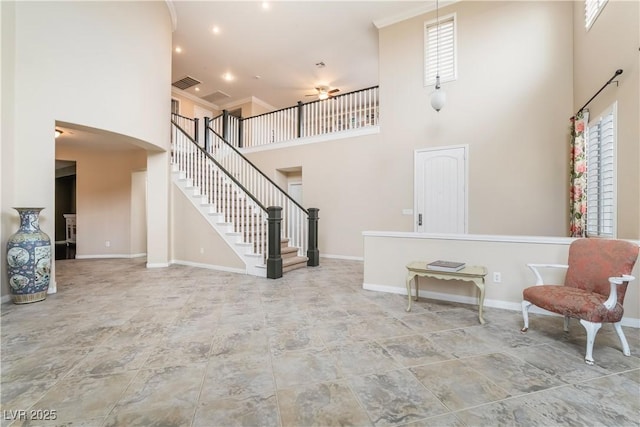 living area featuring ceiling fan, visible vents, baseboards, and a towering ceiling