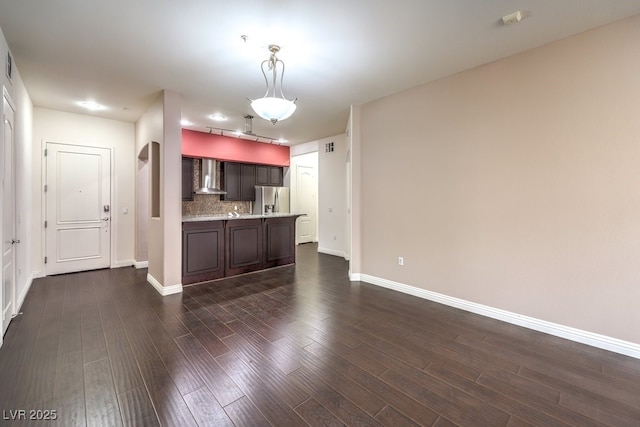 kitchen featuring dark wood finished floors, stainless steel fridge with ice dispenser, dark brown cabinetry, wall chimney exhaust hood, and backsplash