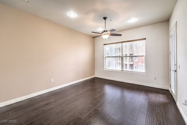 empty room with baseboards, ceiling fan, and dark wood-style flooring