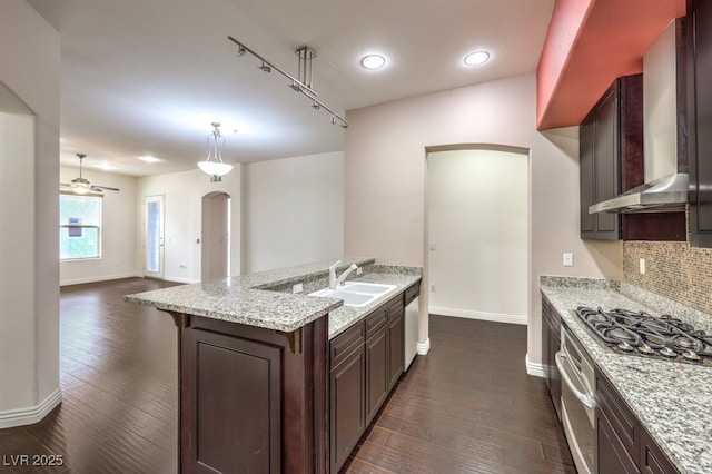 kitchen featuring a sink, gas cooktop, backsplash, wall chimney exhaust hood, and dark wood-style flooring