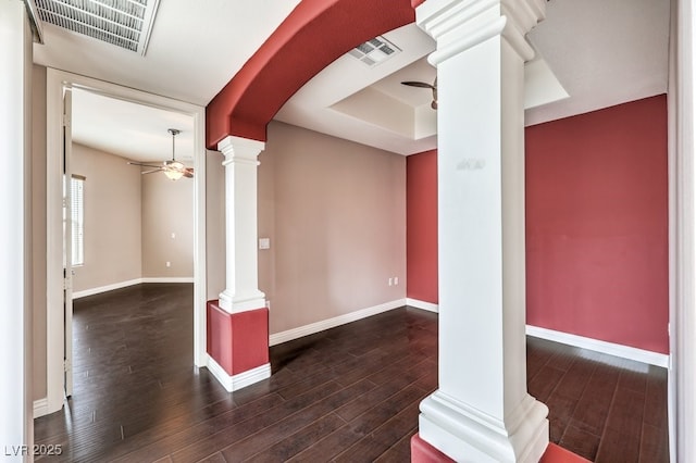 spare room with decorative columns, visible vents, wood finished floors, and a ceiling fan