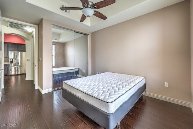 bedroom with visible vents, dark wood-style floors, arched walkways, stainless steel fridge with ice dispenser, and baseboards