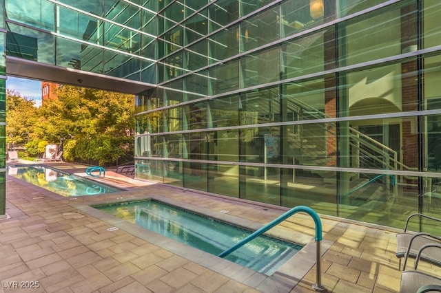 pool with a patio area and an in ground hot tub