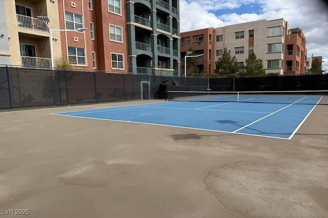 view of tennis court featuring community basketball court and fence