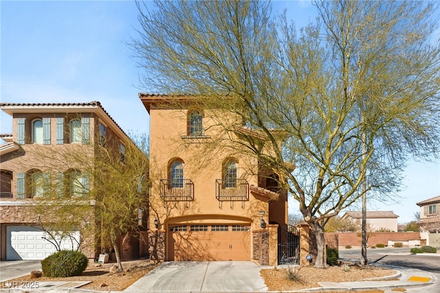 view of front of house featuring a balcony, a gate, an attached garage, stucco siding, and concrete driveway