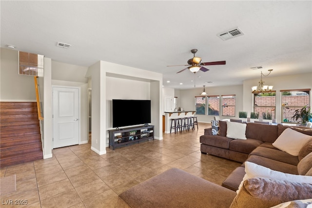 living room with light tile patterned floors, visible vents, and ceiling fan with notable chandelier