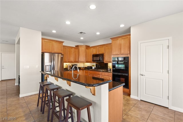 kitchen with light tile patterned floors, a kitchen breakfast bar, black appliances, and recessed lighting