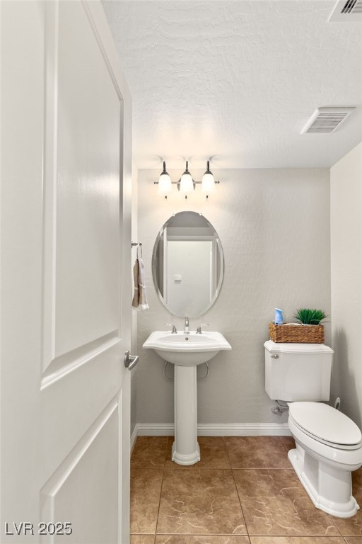 half bath with baseboards, visible vents, tile patterned flooring, a textured ceiling, and toilet