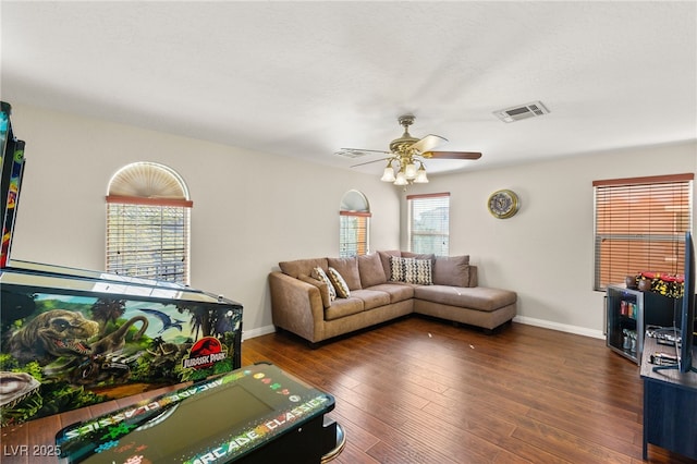 living area with a ceiling fan, visible vents, dark wood-style flooring, and baseboards