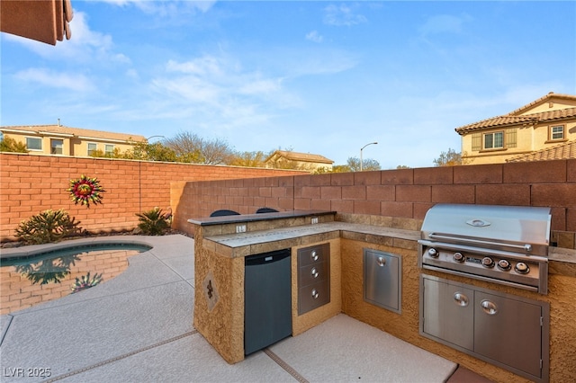 view of patio / terrace with area for grilling, a fenced backyard, and an outdoor kitchen