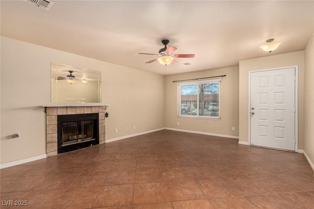 unfurnished living room featuring visible vents, baseboards, ceiling fan, and a tiled fireplace