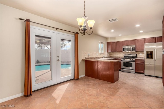 kitchen featuring a peninsula, french doors, appliances with stainless steel finishes, tasteful backsplash, and a chandelier