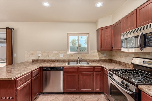 kitchen featuring a sink, recessed lighting, appliances with stainless steel finishes, a peninsula, and decorative backsplash