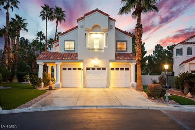 mediterranean / spanish home featuring a tiled roof, an attached garage, driveway, and stucco siding