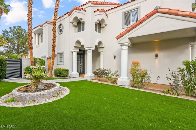 mediterranean / spanish-style house with a front yard, a tiled roof, and stucco siding