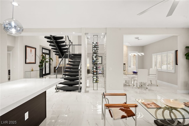 stairway featuring baseboards, marble finish floor, and ceiling fan