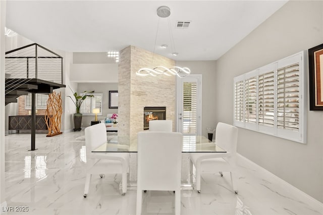 dining space with a fireplace, visible vents, marble finish floor, and baseboards