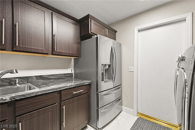 kitchen featuring a sink, washer / clothes dryer, dark brown cabinetry, and stainless steel fridge with ice dispenser