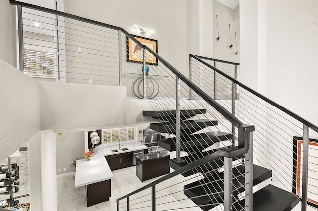 stairs featuring marble finish floor and a towering ceiling