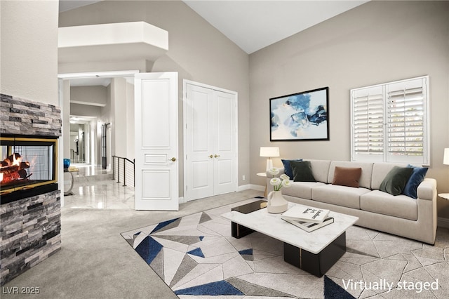 living room featuring baseboards, lofted ceiling, and a fireplace