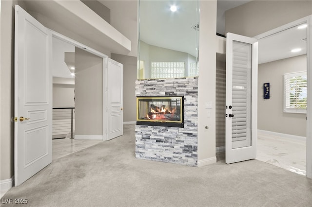 carpeted living area with baseboards, a multi sided fireplace, and lofted ceiling