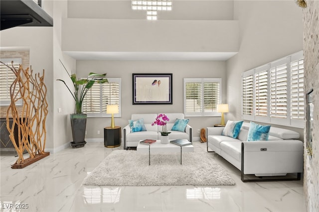 living area featuring baseboards, a high ceiling, and marble finish floor