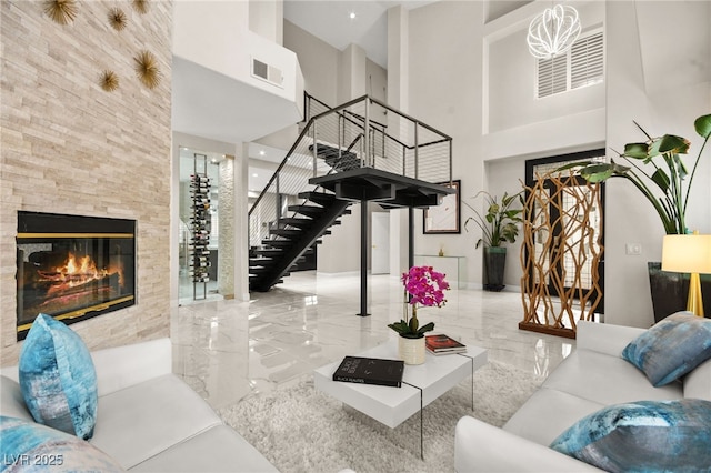 living area featuring visible vents, a high ceiling, stairs, marble finish floor, and a large fireplace