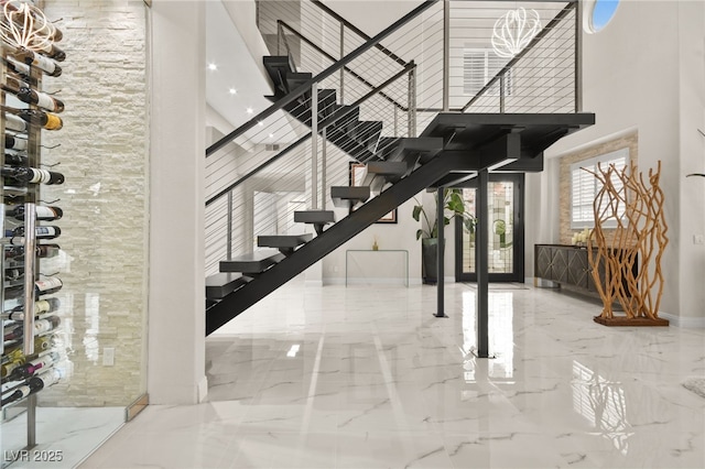 interior space with a high ceiling, baseboards, and marble finish floor