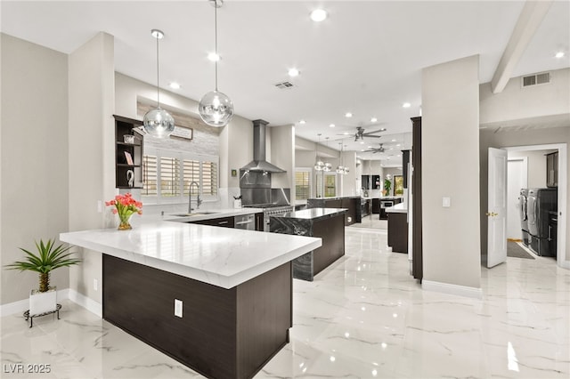 kitchen with washing machine and clothes dryer, visible vents, wall chimney range hood, a peninsula, and marble finish floor