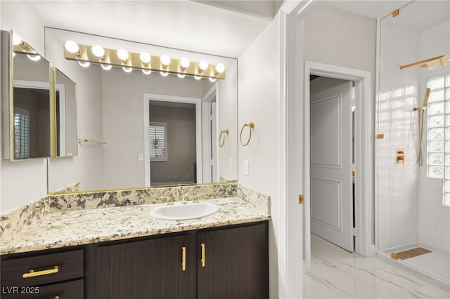 bathroom featuring marble finish floor, vanity, and a tile shower