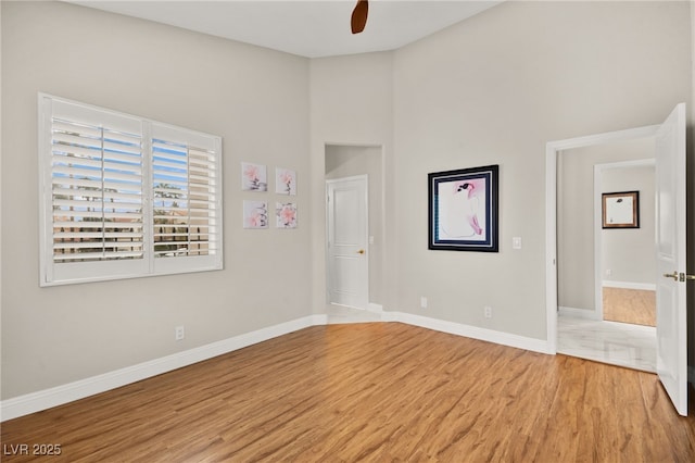 unfurnished bedroom featuring light wood-type flooring, baseboards, and a ceiling fan