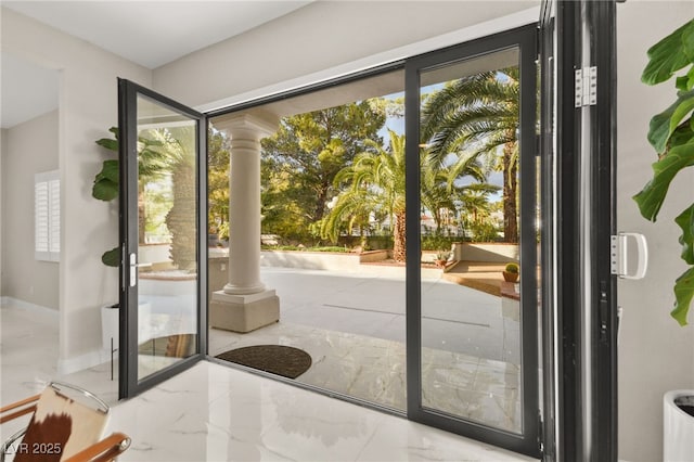 doorway to outside with marble finish floor, baseboards, and decorative columns