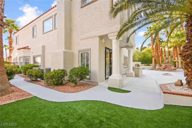 view of property exterior featuring french doors, a patio, a yard, and stucco siding