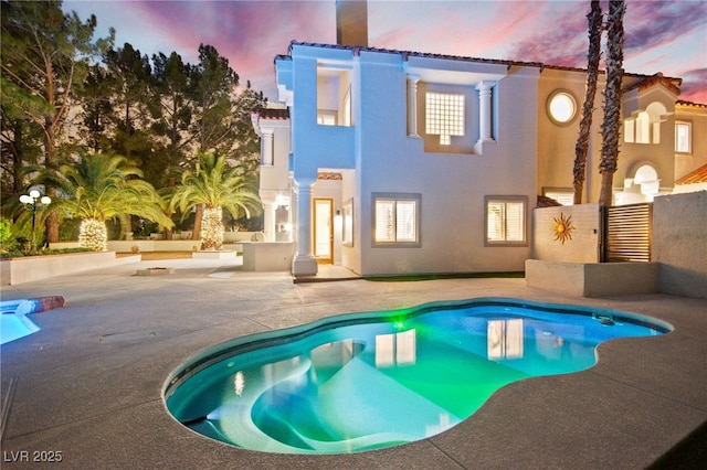 rear view of property with a patio area, stucco siding, and an outdoor pool