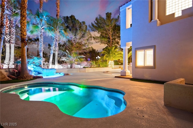 pool at dusk with a jacuzzi and a patio area