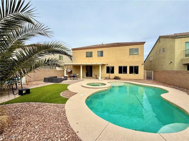 pool featuring an in ground hot tub, an outdoor hangout area, a fenced backyard, and a patio