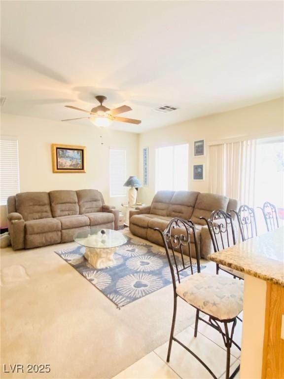 living area with visible vents, a healthy amount of sunlight, and ceiling fan