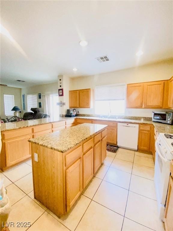 kitchen with white appliances, light tile patterned floors, visible vents, and a kitchen island