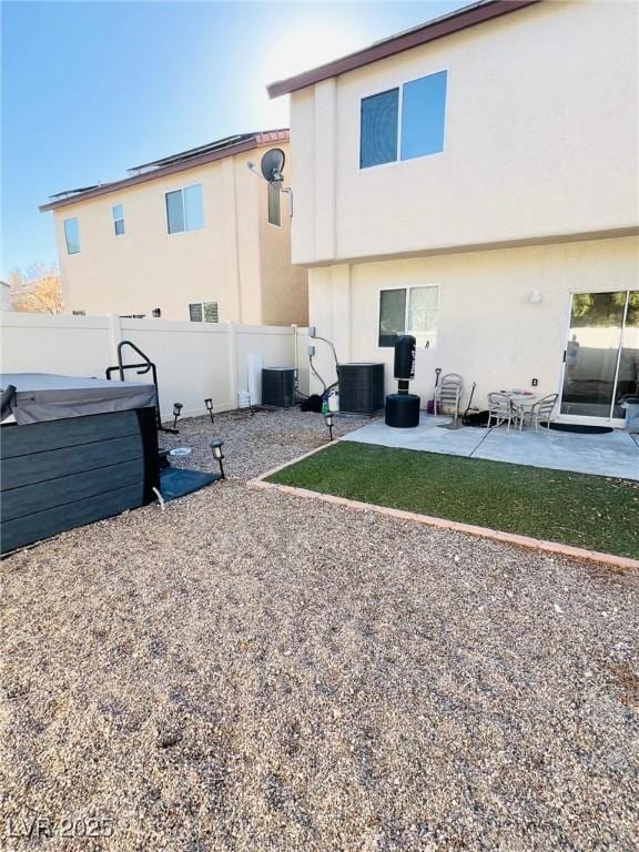 back of house with a patio area, stucco siding, a hot tub, and a fenced backyard