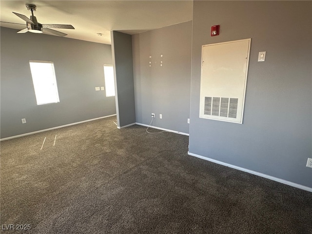 spare room with baseboards, dark carpet, and ceiling fan